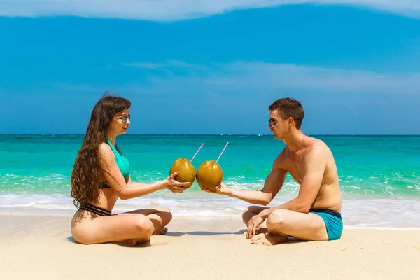 Joven pareja amante beber coco en la playa tropical. Verano vaca — Foto de Stock