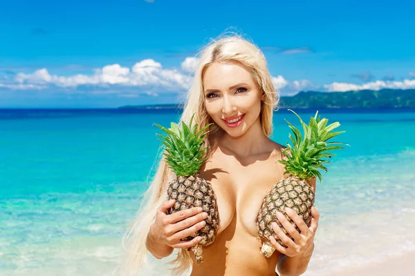 Bella bionda con i capelli lunghi in possesso di due ananas al bre — Foto Stock