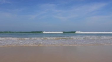 Kumlu sahildeki sakin mavi denizden gelen nazik dalgalar