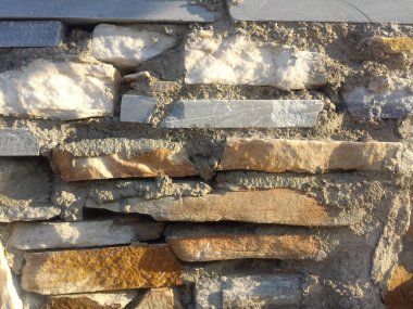 Güneş ışığı arkaplan dokusuna sahip gri ve turuncu taş duvar 