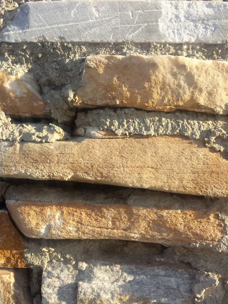 Gri ve turuncu taş duvar dikey arkaplan dokusu ve güneş ışığı yansıması