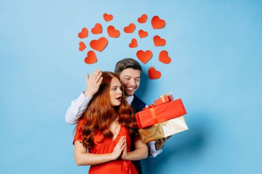 Mavi arka planda izole edilmiş hediyeleri olan şaşırmış kadın ve adam.