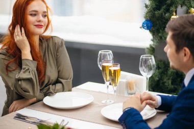 Genç ve güzel bayan ve yakışıklı adam yemek yer, restoranda kutlama yaparlar.