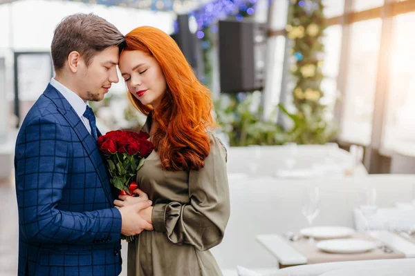 Gorgeous guy in tux and redhaired lady in dress on a date — Stock Photo, Image