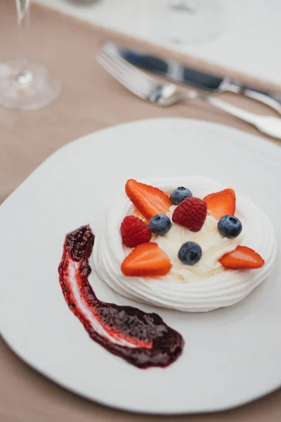 tasty meringue dessert Pavlova cake with fresh berries on white plate