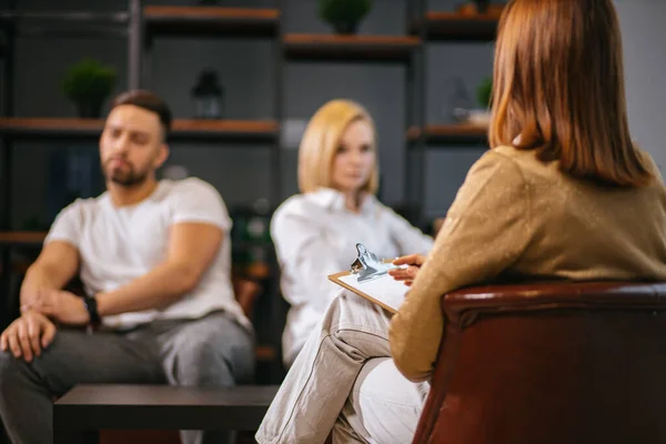 Junges kaukasisches Paar, das sich gegenseitig beleidigt, sitzt beim Familienpsychologen — Stockfoto