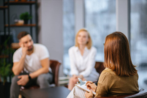 young caucasian couple offended by each other sit at consultation with family psychologist
