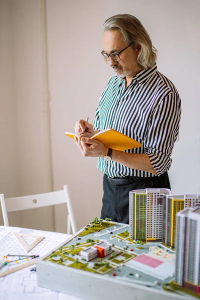 mature builder taking notes in office