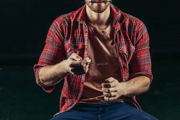 Young junkie man heating drugs in a spoon — Stockfoto