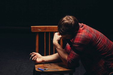 tired man junkie leans on chair