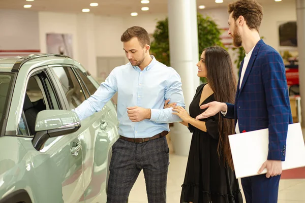 Casal escolhendo novo automóvel na concessionária — Fotografia de Stock