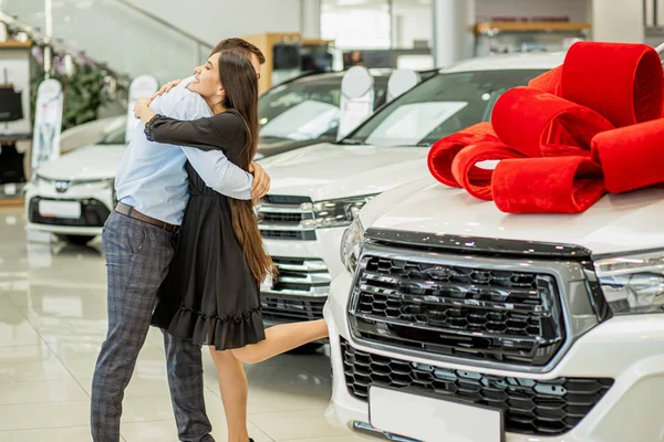 Happy couple hugging on the background of new car — Stockfoto
