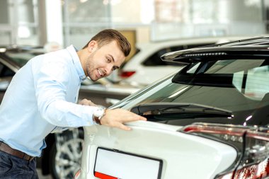 happy caucasian customer examining, checking surface of new car