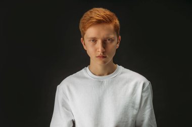 portrait of serious redhead guy isolated over black background