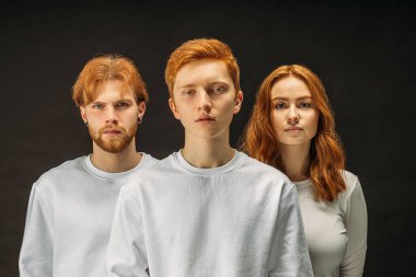 three red haired people isolated on black background