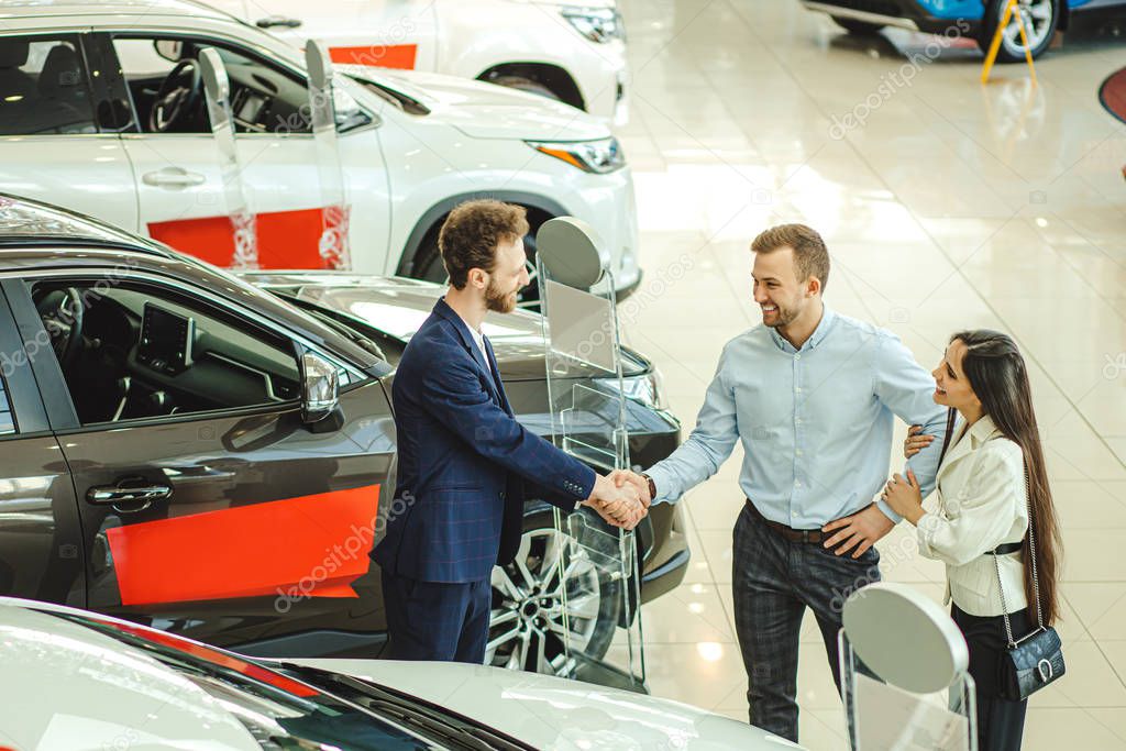 couple greeting a salesman in dealership