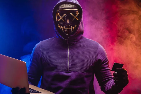 Portrait of hacker in a hood, a hacker on a dark smoky background. — Stockfoto