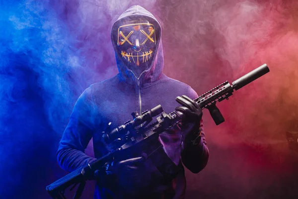 Людина в масці стоїть зі зброєю ізольовано над димчастим простором — стокове фото
