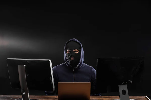 Σοβαρός χάκερ άντρας στο καπό κάθεται με το laptop — Φωτογραφία Αρχείου