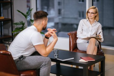 Genç ve güzel bir bayan psikolog hastasıyla ofisinde oturuyor.