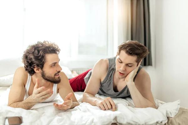 homosexual married couple talking on bed