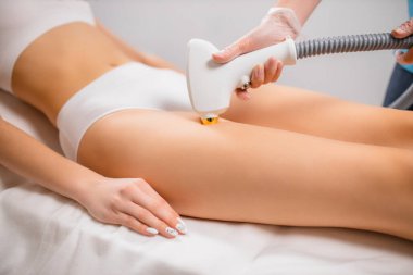 Sıska kadın bacakları ve lazer saç kesimi için aletler.