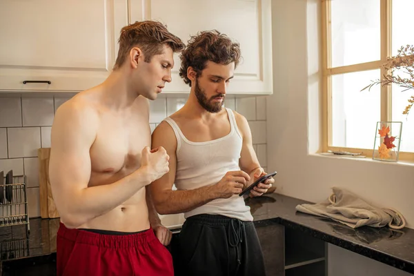 Due omosessuali guardano smartphone, in cucina — Foto Stock