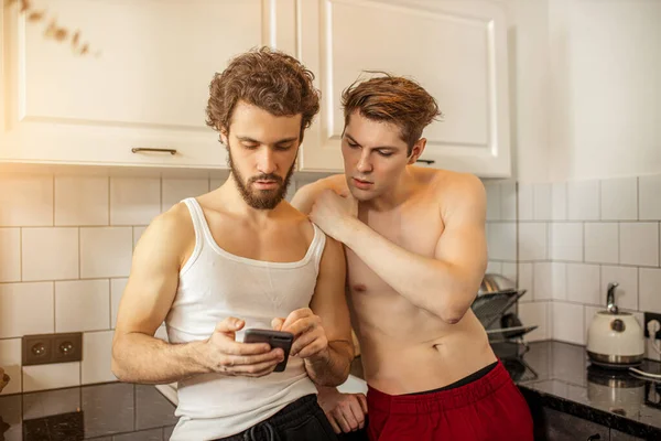 Coppia omosessuale in cucina al mattino, con cellulare — Foto Stock