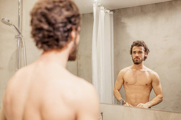 man examining his face in mirror
