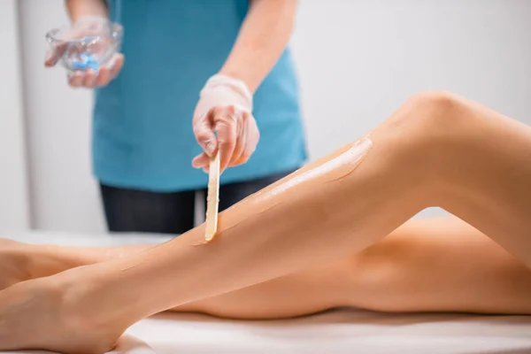 Kosmetyczka stosuje krem nawilżający na kobiece nogi — Zdjęcie stockowe