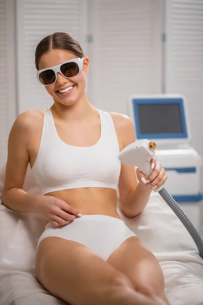 Молодая позитивная улыбающаяся женщина сидит в спа-салоне, получает процедуру удаления волос — стоковое фото