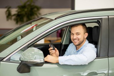 pozitif gülümseyen beyaz adam yeni otomobilin anahtarlarını tutuyor