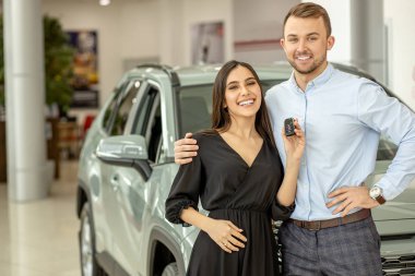 young couple buying their new first car in dealership clipart