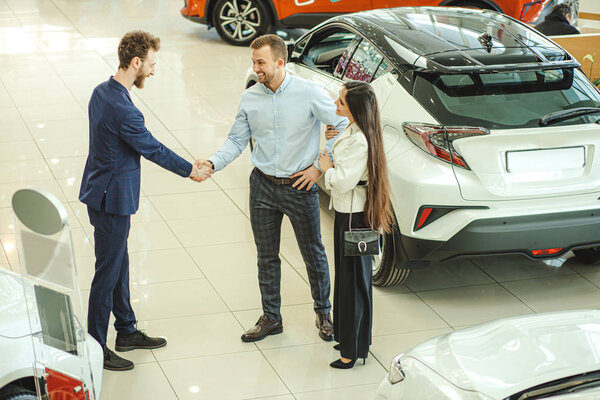 мужчина и женщина приветствуют продавца в салоне
