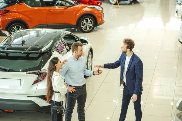 Lindo casal veio para comprar um novo carro na concessionária — Fotografia de Stock