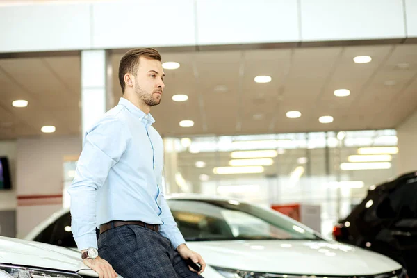 Hombre de negocios con su nuevo coche en la concesionaria — Foto de Stock