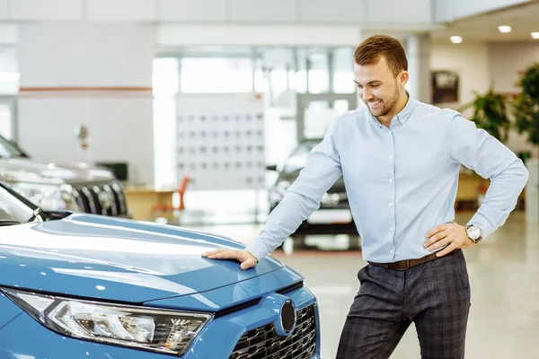 Vista lateral no homem que olha para o automóvel novo no salão de beleza do carro — Fotografia de Stock