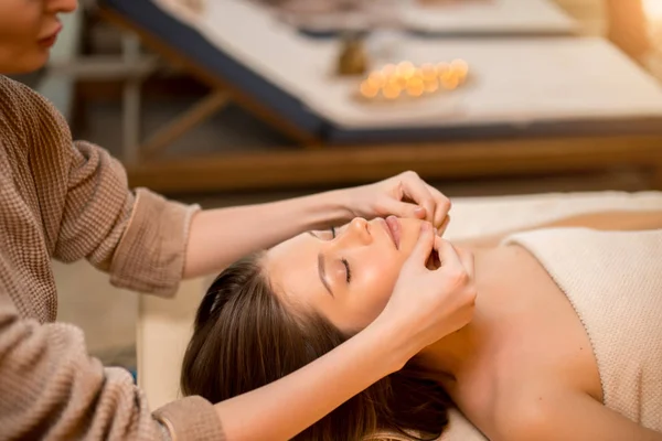Mujer tranquila vino a recibir masaje en la cara, en el salón de spa —  Fotos de Stock