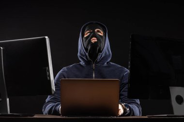 Mahalledeki düşünceli hacker dizüstü bilgisayarla oturuyor.
