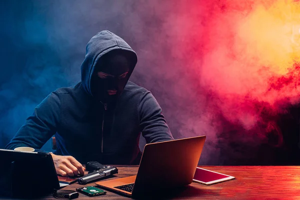 Un hacker dans un capot, un hacker sur un fond sombre et fumé . — Photo