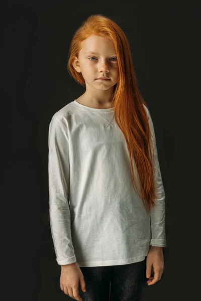 Portrait of serious little girl with long red hair isolated on black — 스톡 사진