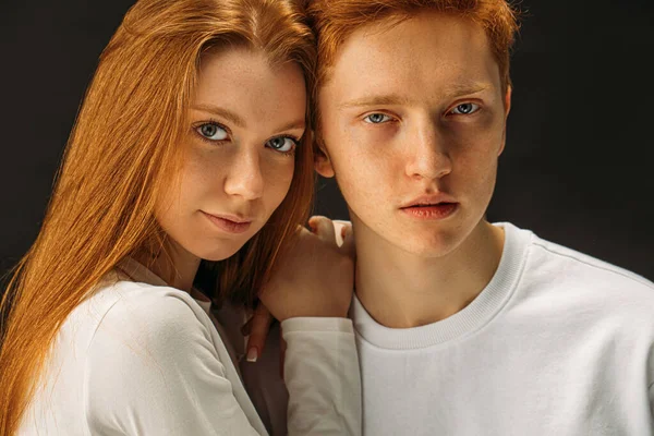 red haired male and female posing together at camera isolated in studio