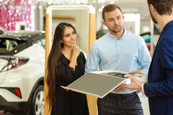 Young couple choosing new car in showroom. service, selling — Stockfoto