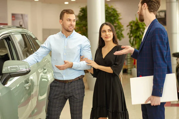 Pareja joven en busca de hermoso coche nuevo — Foto de Stock