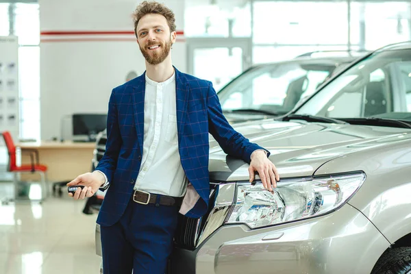 Novo proprietário de carro representativo posando na câmera na concessionária — Fotografia de Stock