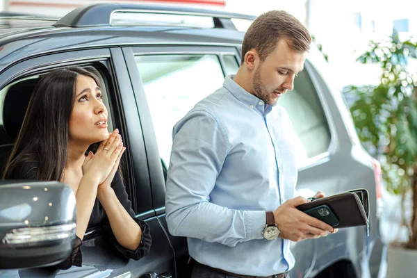 Young caucasian lady begs her husband to buy new car — Stockfoto