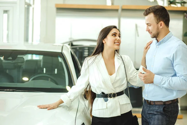 Belo casal com novo carro na concessionária — Fotografia de Stock