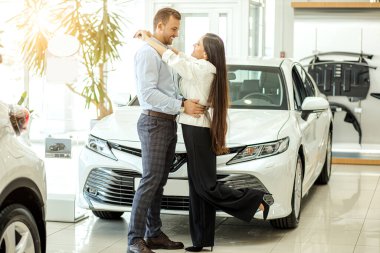 new owners of beautiful car in showroom