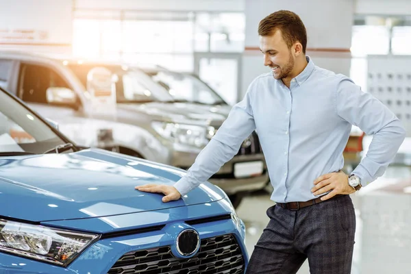 Novo proprietário de carro representativo posando na câmera na concessionária — Fotografia de Stock