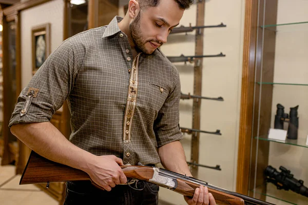 Caçador profissional caucasiano à procura de melhor rifle na loja de armas — Fotografia de Stock